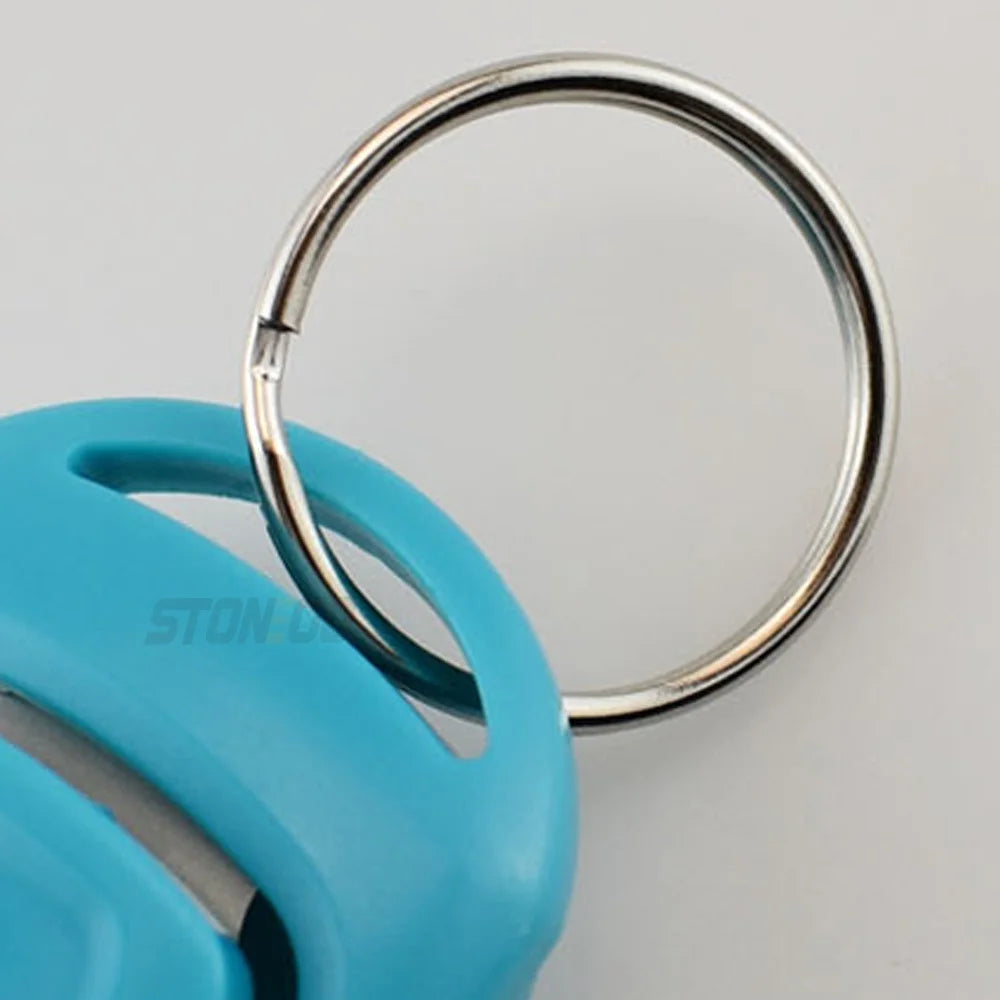 A close-up of a light blue dog training clicker and whistle attached to a silver keyring.