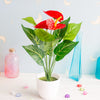 Plante d'anthurioème rouge vif artificielle dans un pot blanc sur fond bleu clair.