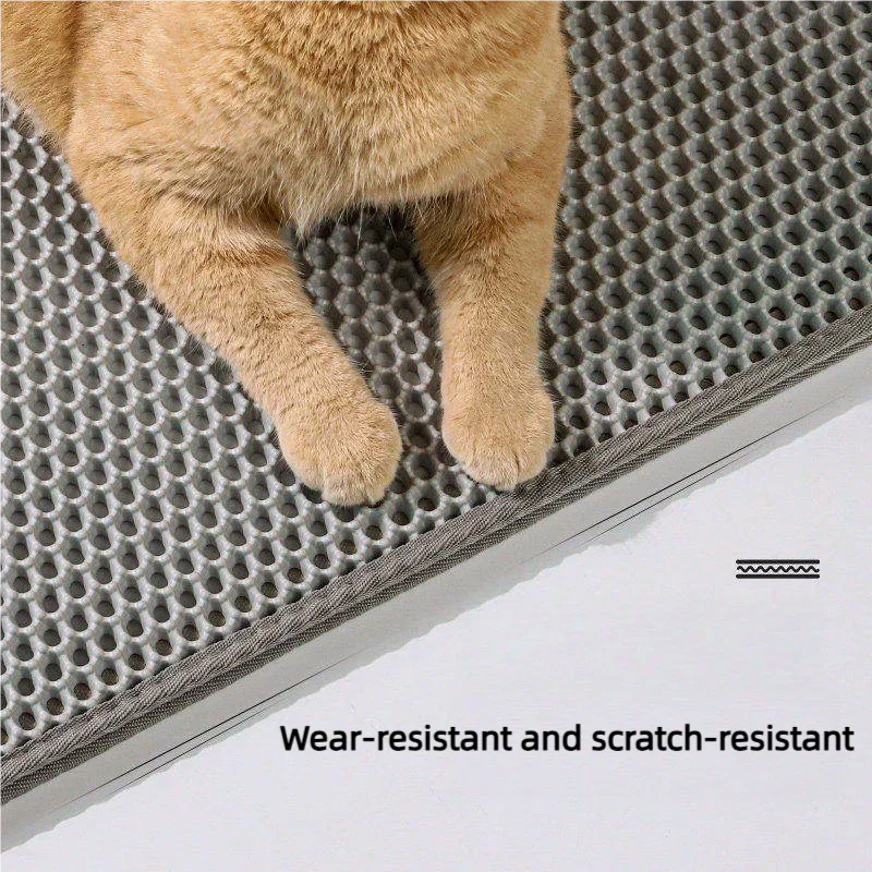 A fluffy orange cat paw rests on a gray, textured litter mat designed to be wear-resistant and scratch-resistant.