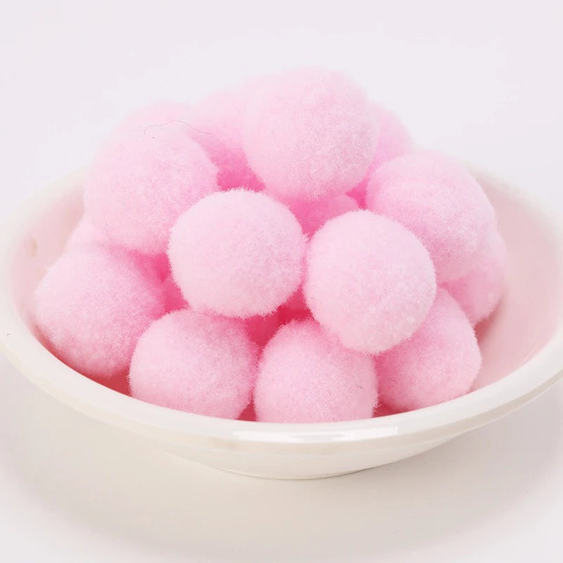 Eine Schale gefüllt mit rosa, flauschigen Katzenhaarkugeln-Spielzeug.