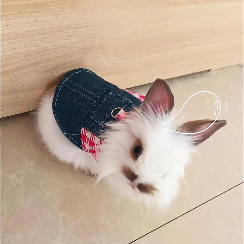 Ein weißer Hase in einem Jeans-Kaninchenkostüm mit roten karierten Akzenten liegt auf einer hellen Holzoberfläche.