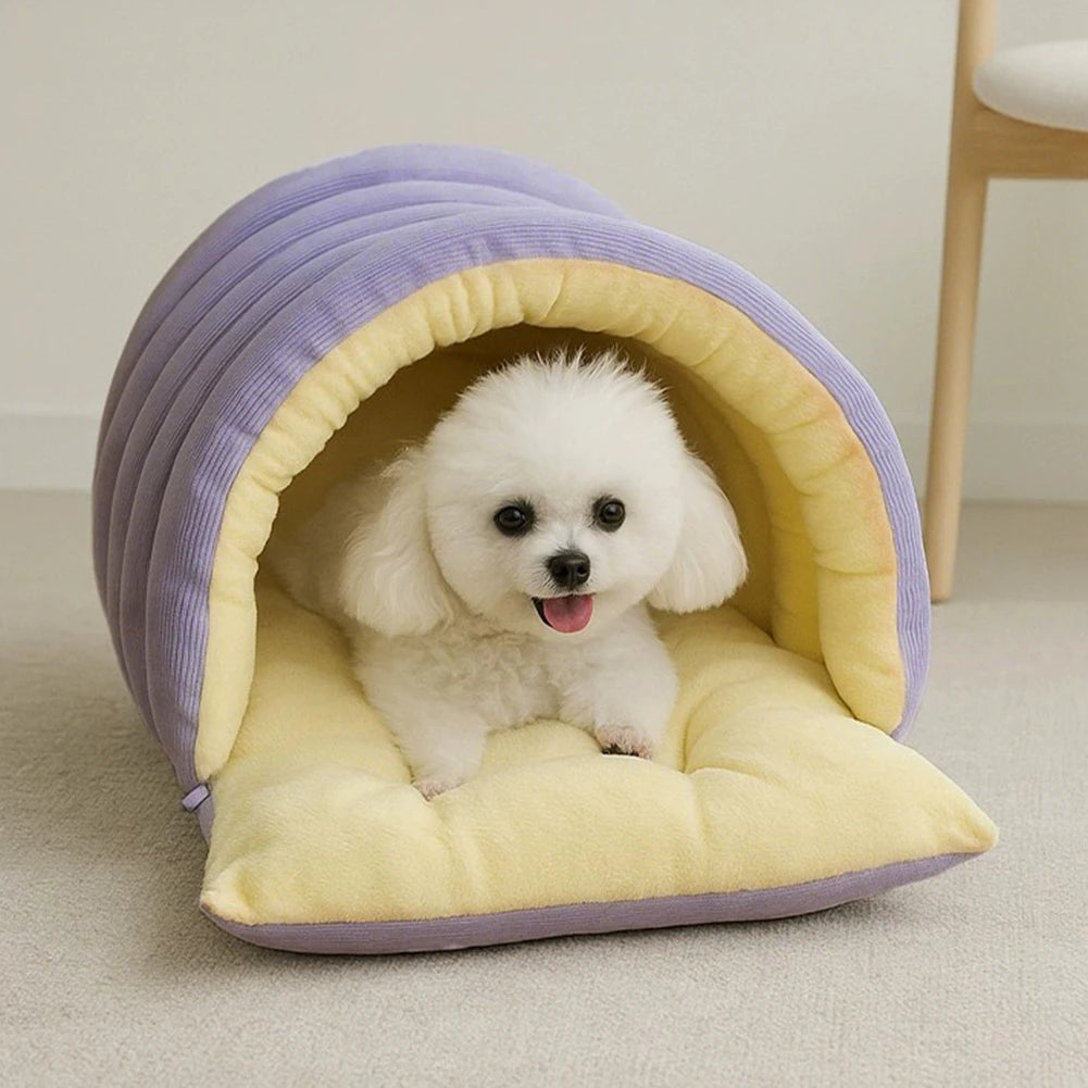 A small white dog is relaxing inside a purple and yellow plush cat cave bed.