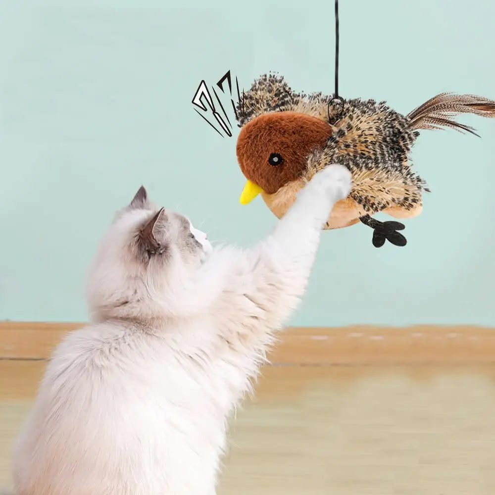 A white cat is reaching for a fluffy, bird-like toy with brown and black feathers hanging from above.