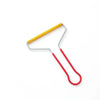 A manual lint remover brush with a metal frame and a yellow handle and a red cord.