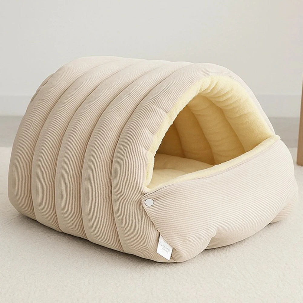 A beige plush cat cave bed with ribbed fabric and a removable inner lining is shown on a light surface.