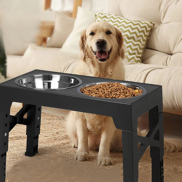 A light-colored Golden Retriever dog is sitting next to a black adjustable stainless steel dog feeder bowl on a carpet.