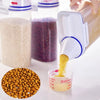 A clear airtight pet food storage container is shown with various colored pet food ingredients, including grains and pellets,