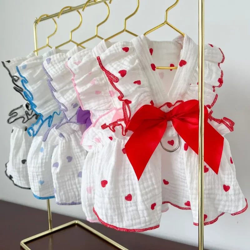 Weißes Hundekleid mit Herzmuster und roter Schleife an einem goldenen Drahtgestell