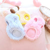 Three fluffy velvet pet sweaters in blue, yellow, and pink are displayed on a pink fabric.