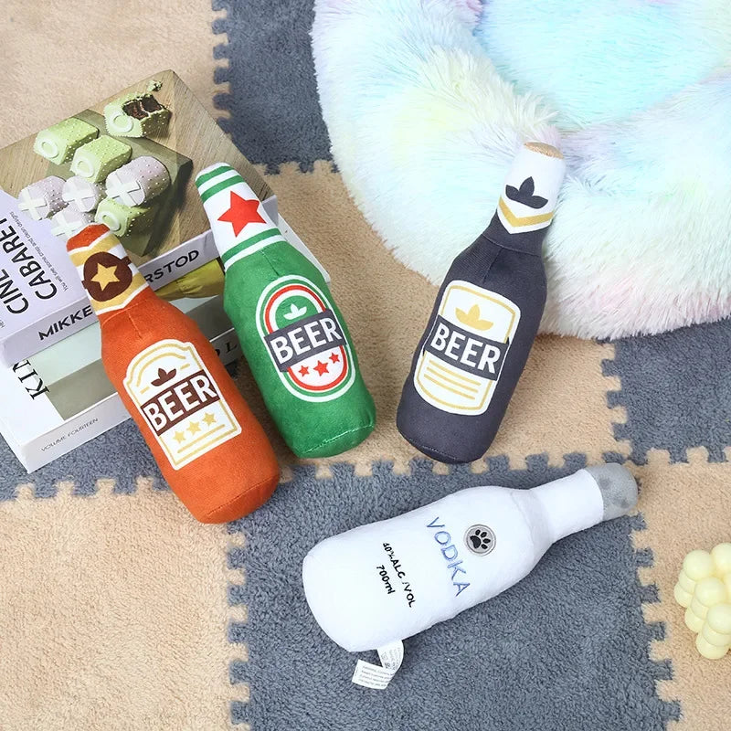 A collection of plush beer bottle dog toys in various colors and designs resting on a fuzzy blanket.