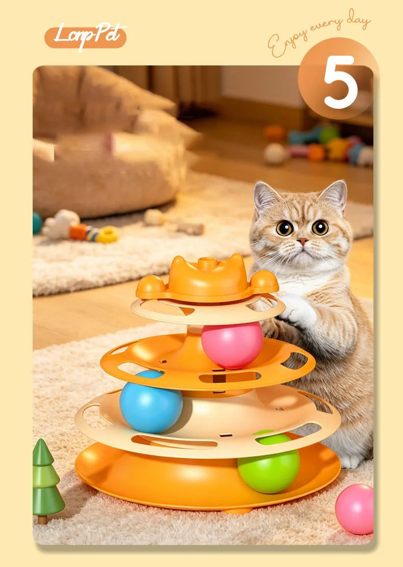 A fluffy orange cat sits next to an orange interactive cat turntable toy with colorful balls.