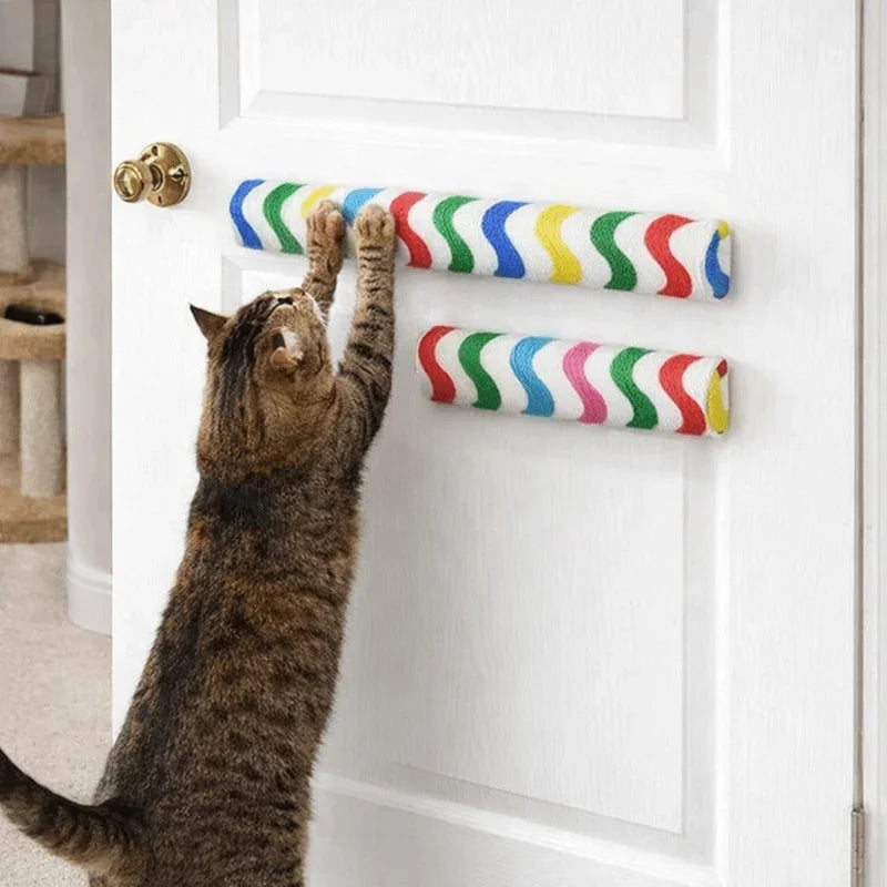 A tabby cat is batting at a colorful, striped wall-mounted scratching board on a white door.