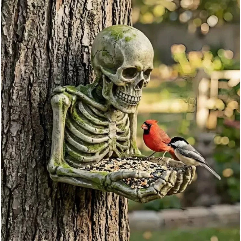 A weathered skull and skeleton sculpture made of resin attached to a tree trunk, with a small bird perched nearby.