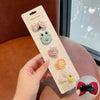 A hand holds a white card displaying five flower-shaped baby hair clips in various colors and textures.