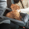 A fluffy brown dog is resting inside a portable pet car seat and booster bed in a car interior.