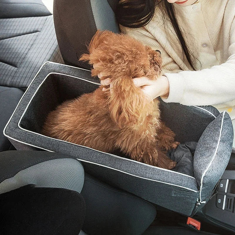 A fluffy brown dog is resting inside a portable pet car seat and booster bed in a car interior.