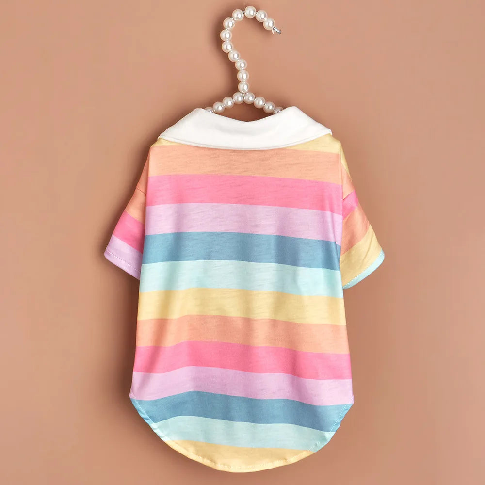 A pink, blue, and yellow striped polo shirt for a small dog is displayed on a hanger.