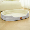 A light beige washable waterproof dog bed mat resting on a wooden floor next to a large cream-colored cushion.