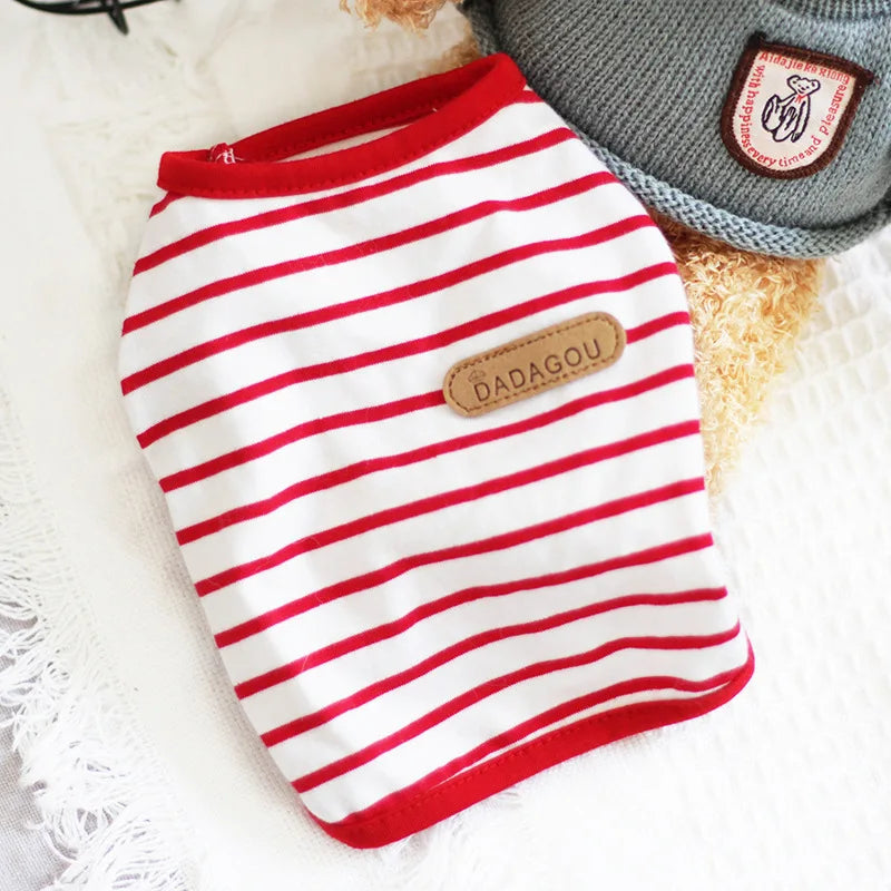 A red and white striped sleeveless vest for a small dog or cat is displayed on a white surface.