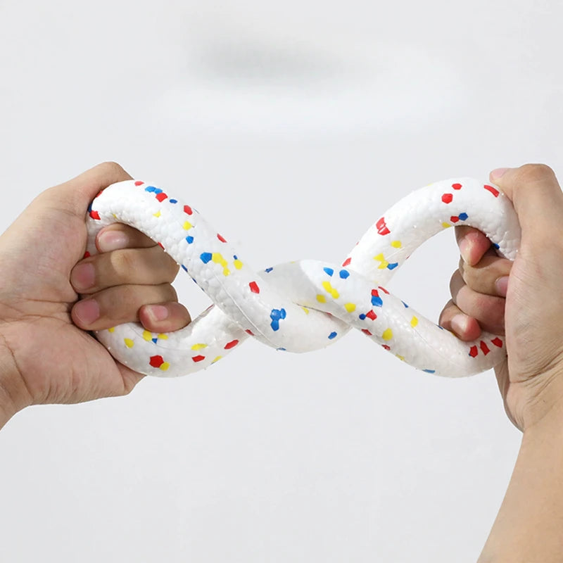 A pair of hands is holding a white, braided chew toy with colorful dots in an intertwined shape.