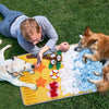 A dog and a person are interacting with a yellow mat filled with various tissue paper shapes for pet sniffing and training.