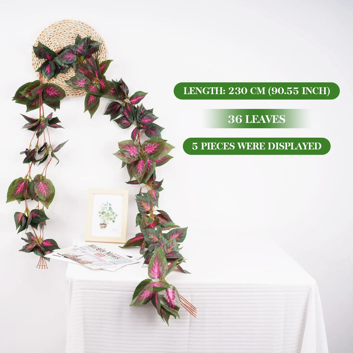 Lange künstliche Blätterrank-Girlande mit rosa und grünen Blättern auf einem weißen Tisch.