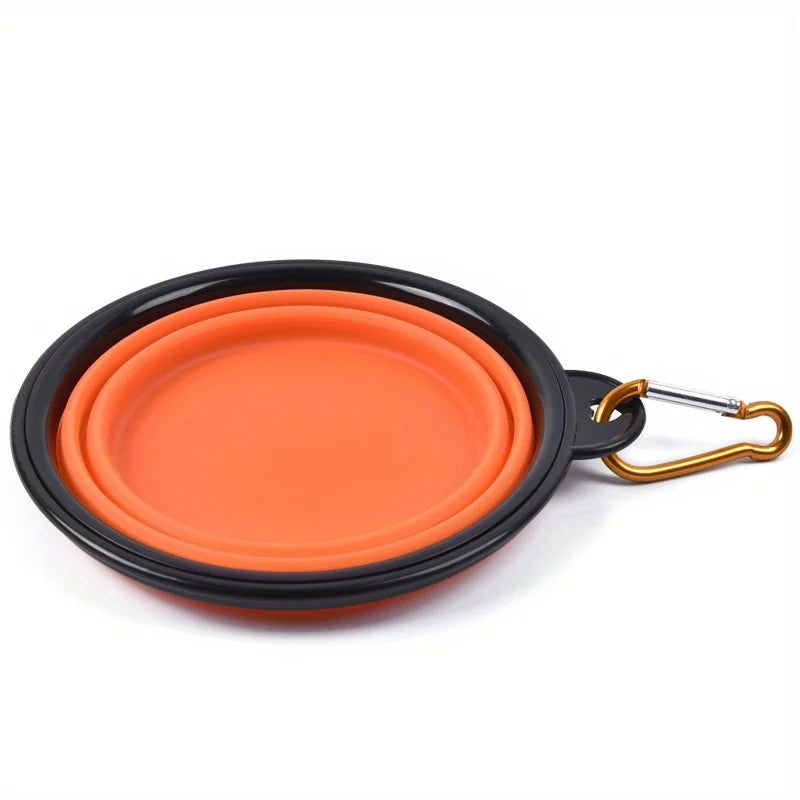 Orange silicone dog travel bowl with a black rim and gold clasp.