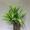 A vibrant green and yellow artificial tropical palm plant with long, pointed leaves displayed against a light gray background