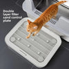A tabby cat is jumping onto a white double layer filter sand control plate for litter box use.