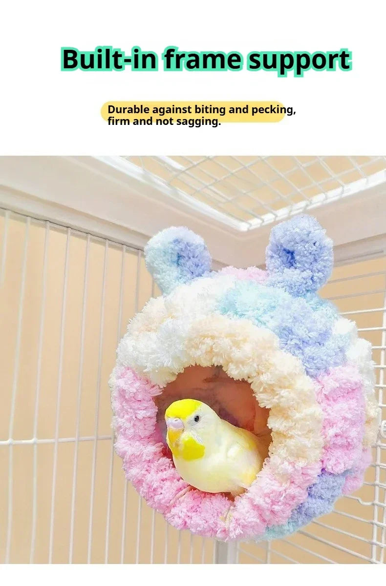 Ein flauschiges, buntes Flanell-Vogelnest mit einer runden Öffnung vor einem Draht-Hintergrund.