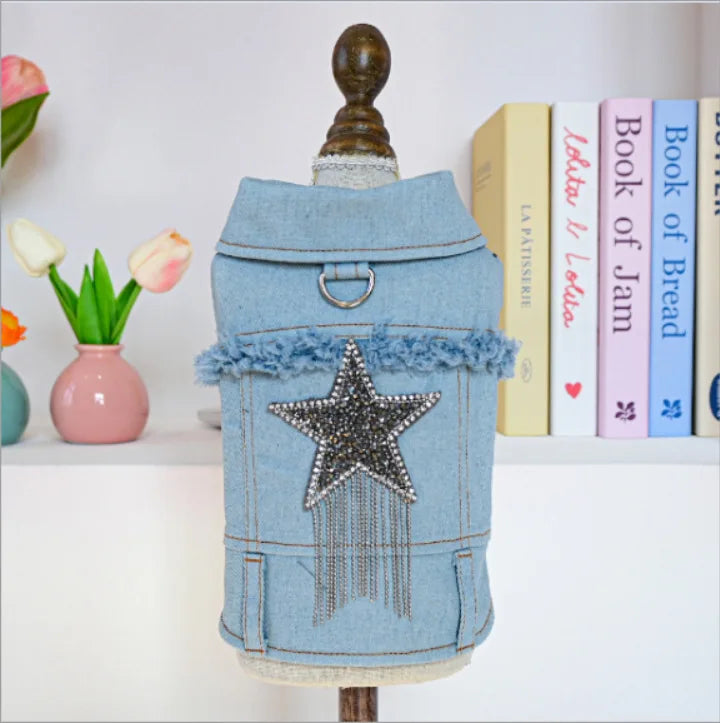 A light blue denim jacket shaped like a vintage suitcase with a gold-colored handle and a silver star decoration.