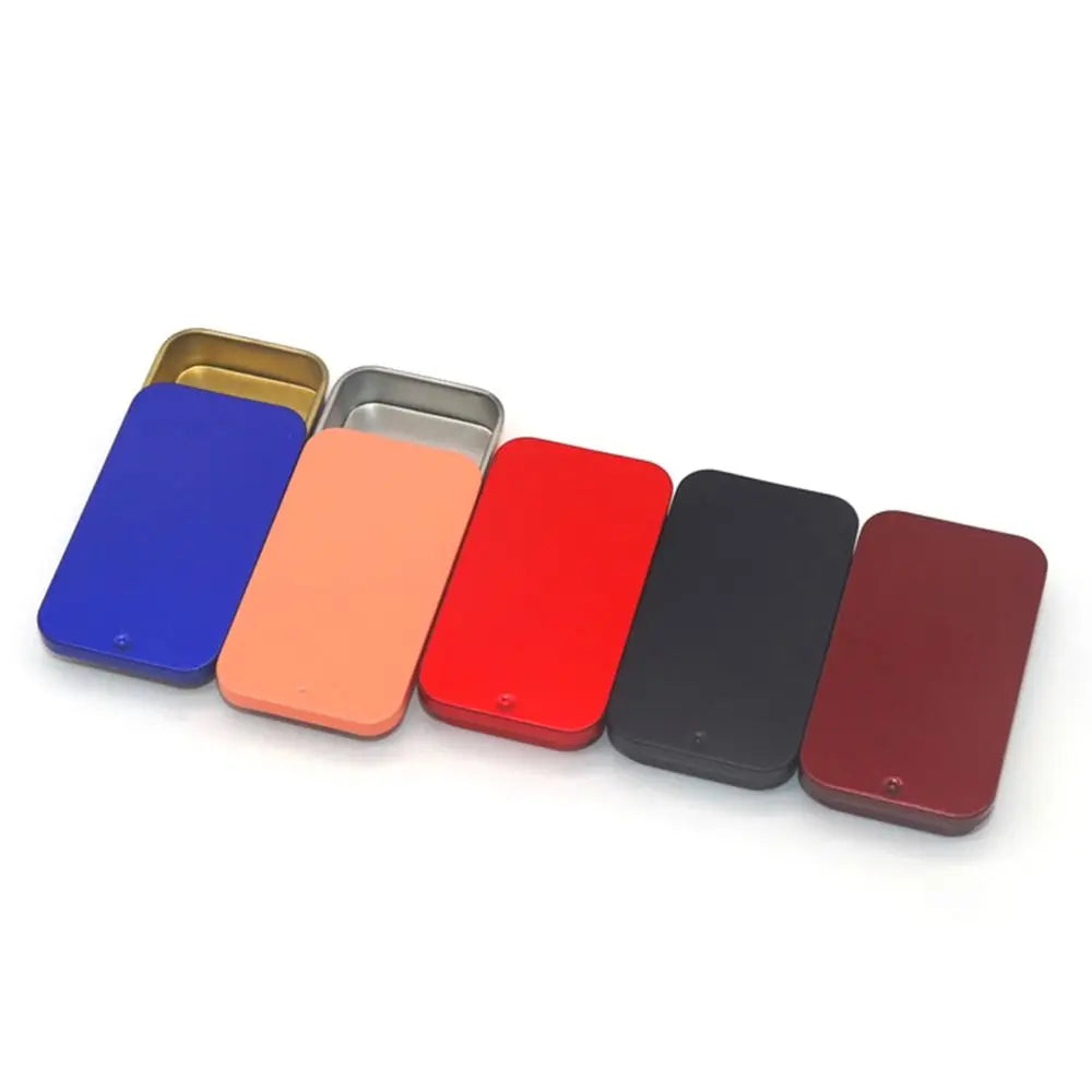 A row of six compact sliding lid tin boxes in various colors including blue, orange, red, black, and maroon.