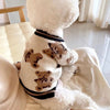 A white knit sweater with brown bear patterns is shown on a small dog or cat.