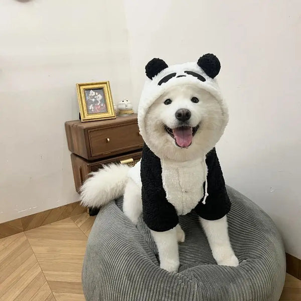 A white and black panda-themed fleece dog coat is sitting on a gray fabric object.