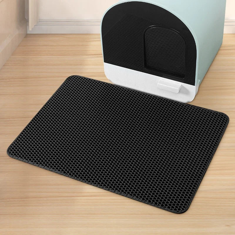A black double-layer cat litter mat is shown in front of a light green and black litter box.