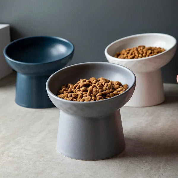 Three elevated ceramic bowls for pet food and water, in shades of blue, gray, and white.