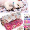 A rolled soft fleece pet bed mat cover with paw print designs, shown next to a sleeping puppy.