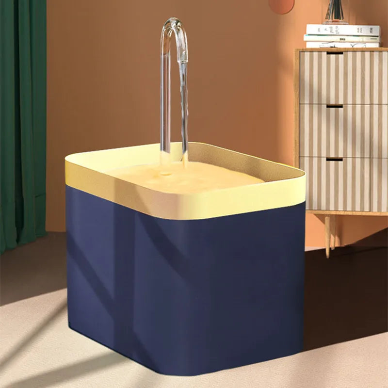 A blue water fountain with a yellow basin and a clear water stream, set in a room with a wooden cabinet.