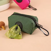 Pochette à fermeture éclair vert foncé avec un mousquet noir, à côté d'un sac plastique vert froissé.