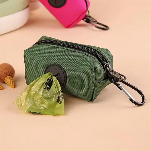 Pochette à fermeture éclair vert foncé avec un mousquet noir, à côté d'un sac plastique vert froissé.
