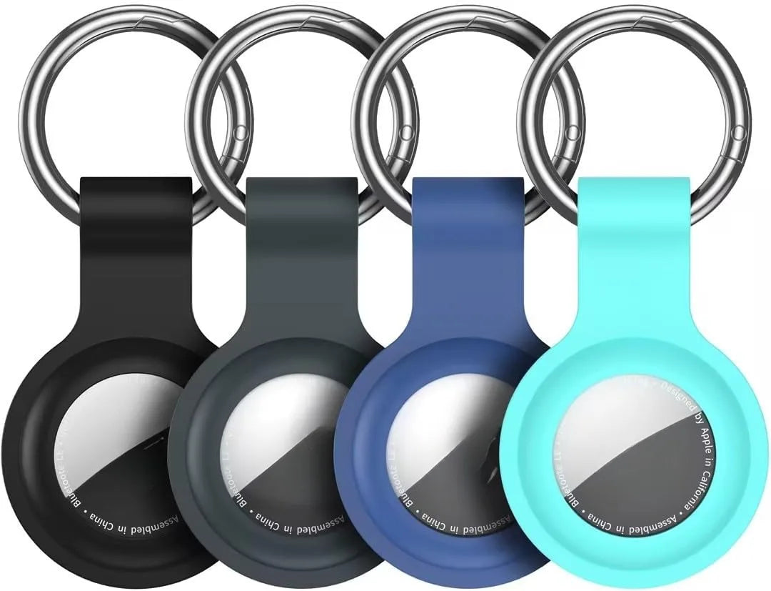 A silicone airtag protective cover is shown attached to a metal keychain ring in various colors: black, gray, blue, and cyan.