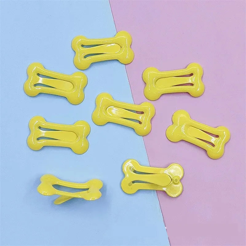 Yellow bone-shaped hair clips arranged on a light blue and pink background.