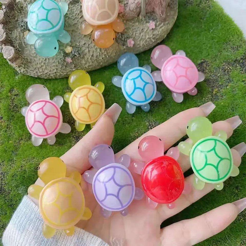 Eine Hand hält mehrere bunte leuchtende Harntier-Ornamente auf einer grünen Oberfläche.