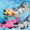 A golden retriever is swimming in the water wearing a gray and white dog life jacket.