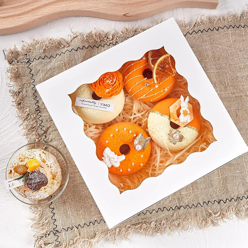A white plate features ten orange and yellow window cakes with secure bases arranged on a rustic cloth.