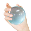 Eine Hand drückt eine durchsichtige blaue Knetball-Stressbälle.