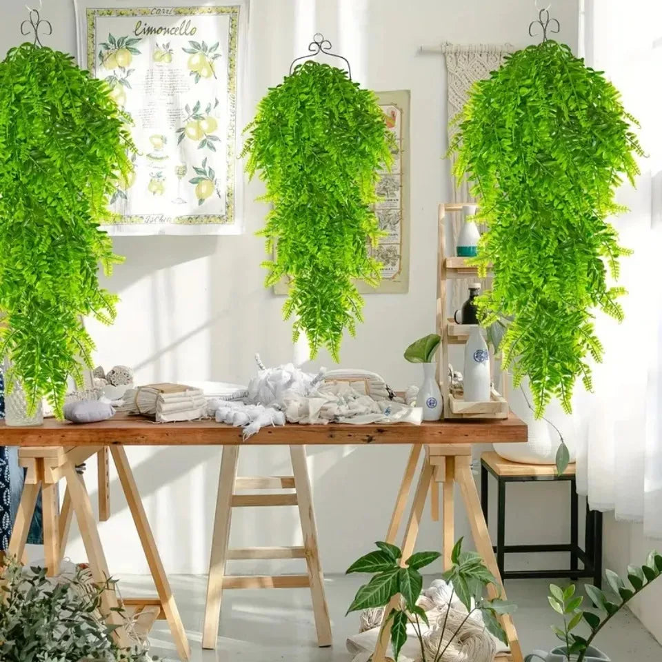 Four artificial green Persian fern hanging vines displayed on a wooden table.