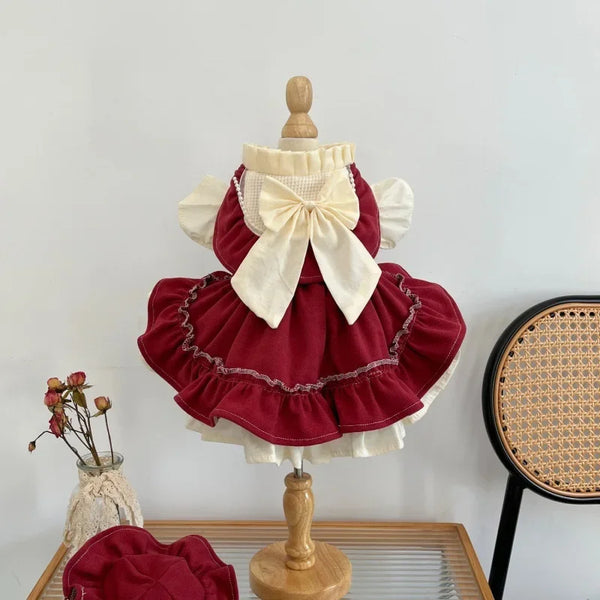A red pet princess dress with a large bow displayed on a wooden mannequin.