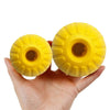 A hand holds two yellow rubber fetch balls with textured surfaces.