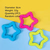 Four rubber chew toys in pink, blue, and yellow colors displayed on a light background.